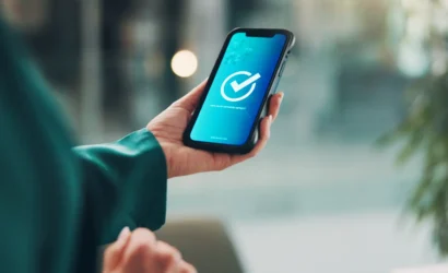 Osoba drží smartfón s ikonou potvrdenia ako symbol elektronického hlasovania vlastníkov bytov v digitálnej správe bytového domu.