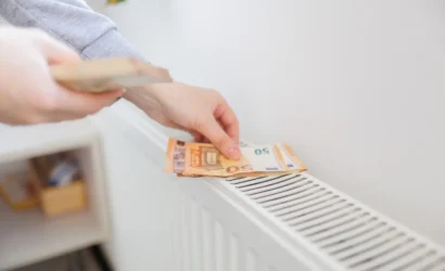 Eurobankovky položené na radiátore ako symbol vysokých nákladov na kúrenie v bytovom dome.
